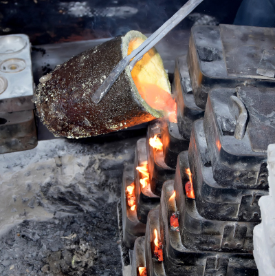 Antike Beschlaege - Fluessiges Messing wird in die Sandform gegossen